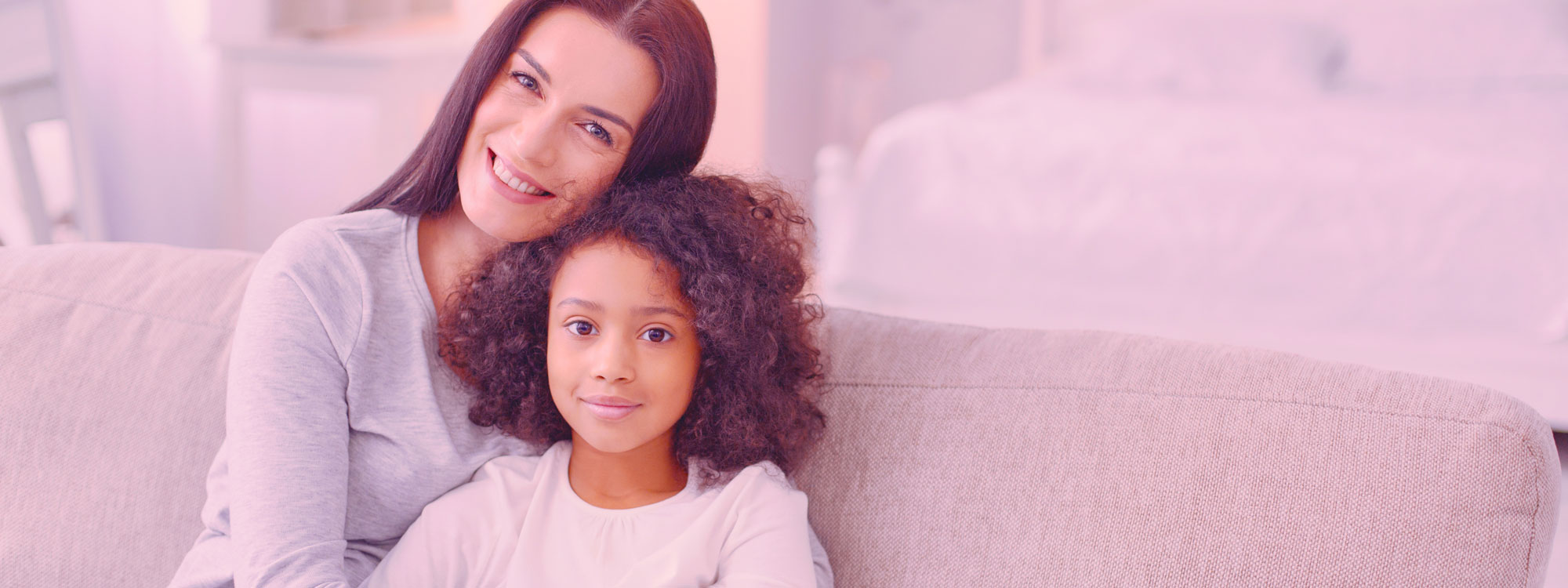 Young girl sitting in the lap of a woman - both smiling.