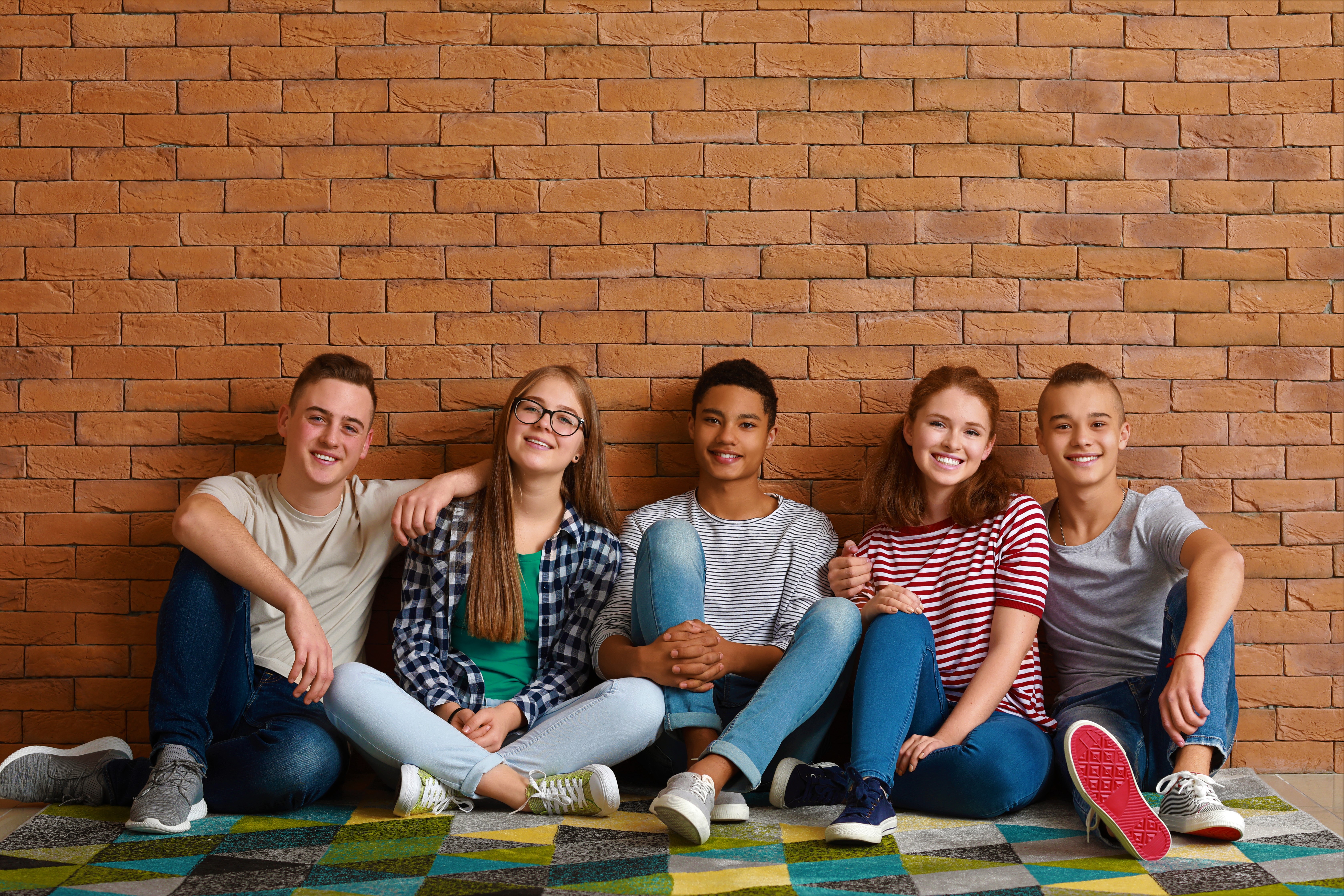 Teens sitting against wall.